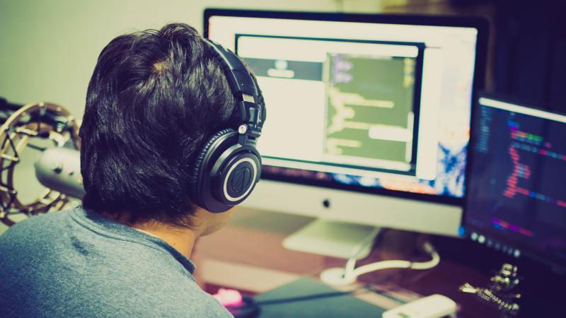 person studying information at computer with headphones one