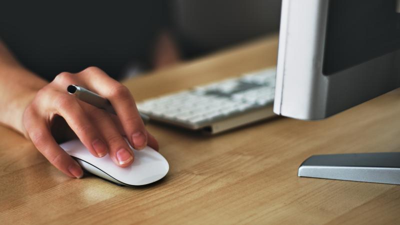 hand using mouse next to computer